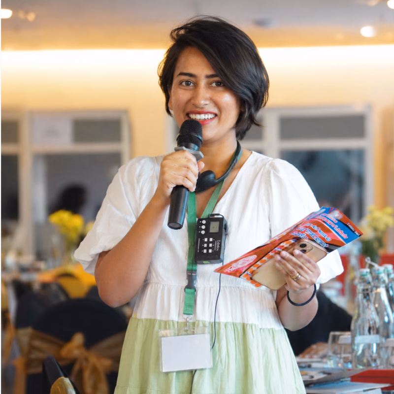 Suman Saurav speaking into a microphone at a gathering